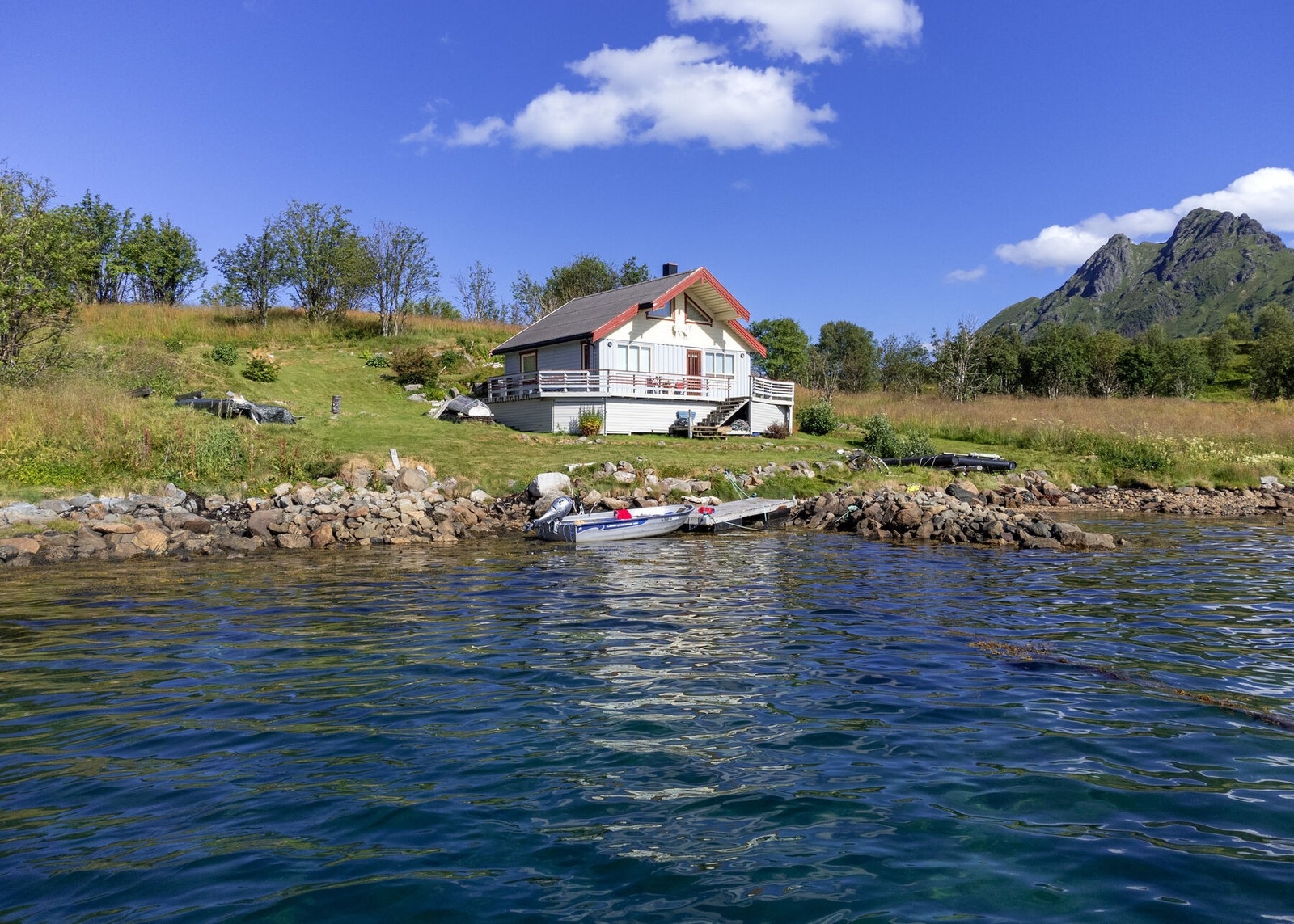 Hytten og uteområdet sett fra sjøen. Galleribilde