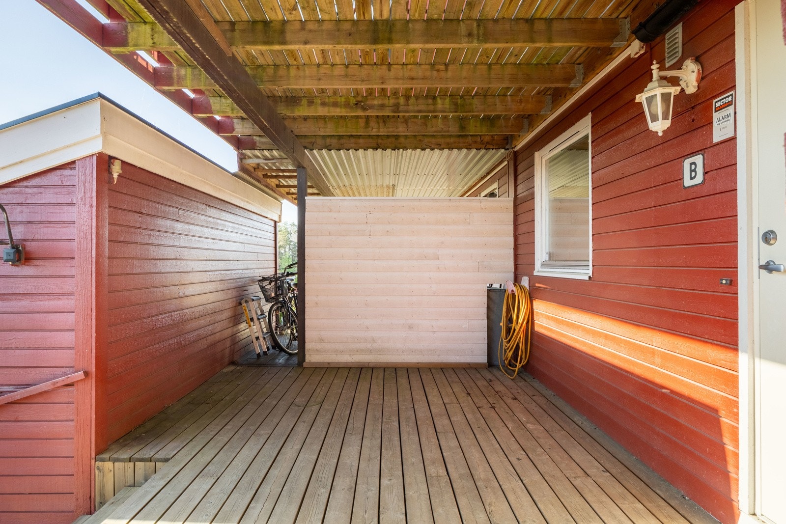 Boligens inngangsparti har en stor terrasse og utvendig bod. Galleribilde