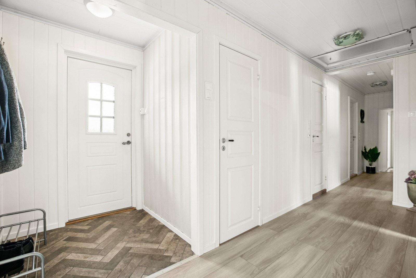 Entréen er lys, fin og romslig. Ved ytterdøren er det fliser i fiskebensmønster og lengre inn er det enstavs laminat. Galleribilde