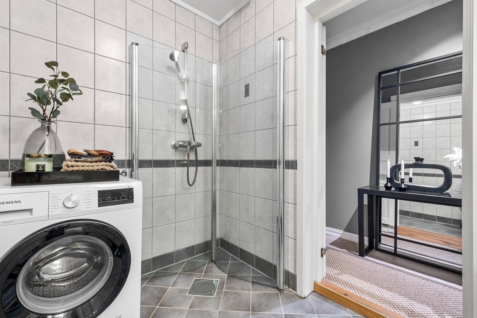 Badet er ellers innredet med stor dusj med dusjdører i herdet glass, gulvmontert toalett, og opplegg for vask/tørk. Galleribilde