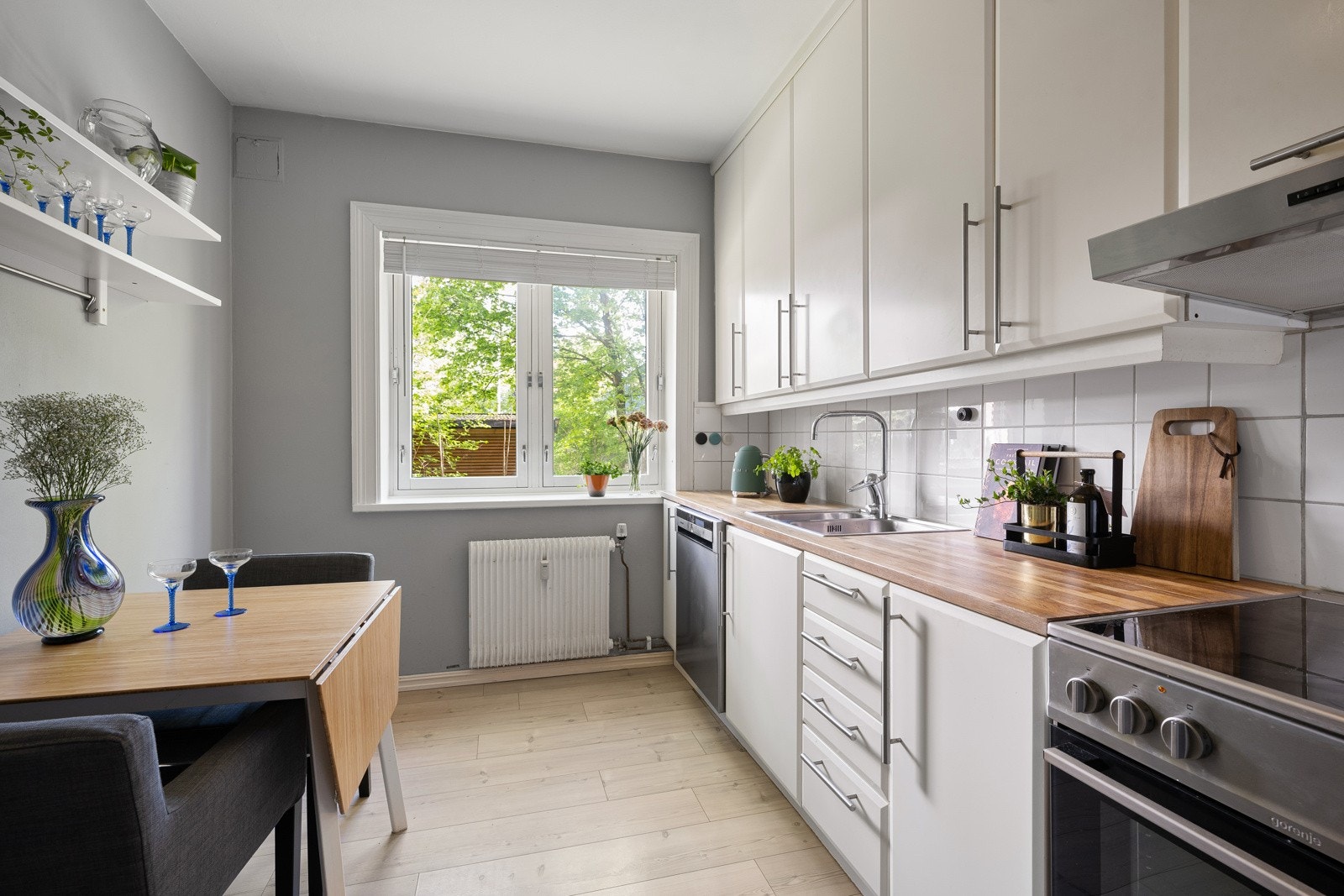 Leiligheten har et separat kjøkken med foliert glatt innredning, heltre eik benkeplate med nedfelt stålkum, fliser over benk og belysning under overskap. Galleribilde