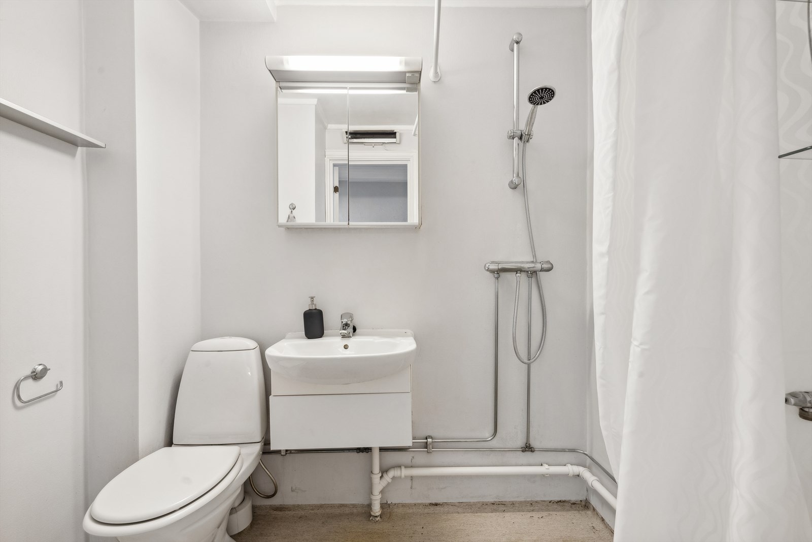 Lyst baderom med malt betong på vegger og gulv med linoliumbelegg. Galleribilde