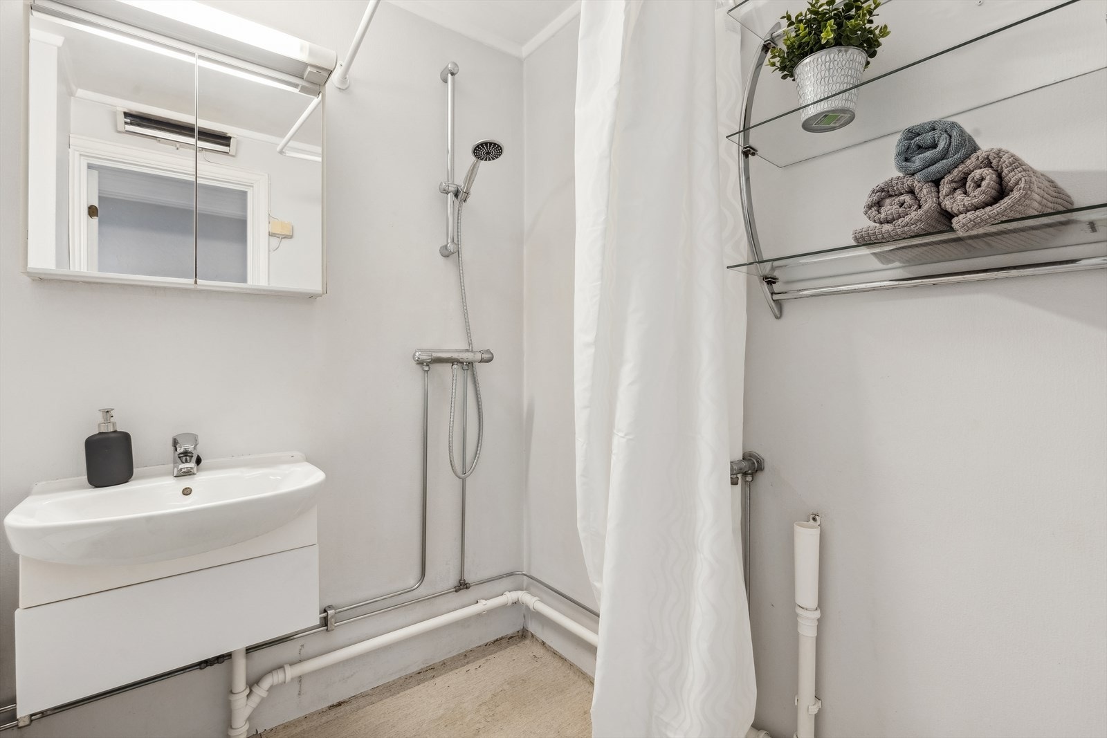 Badet er innredet med klosett, servant og dusjhjørne. Opplegg for vaskemaskin og naturlig avtrekk. Galleribilde