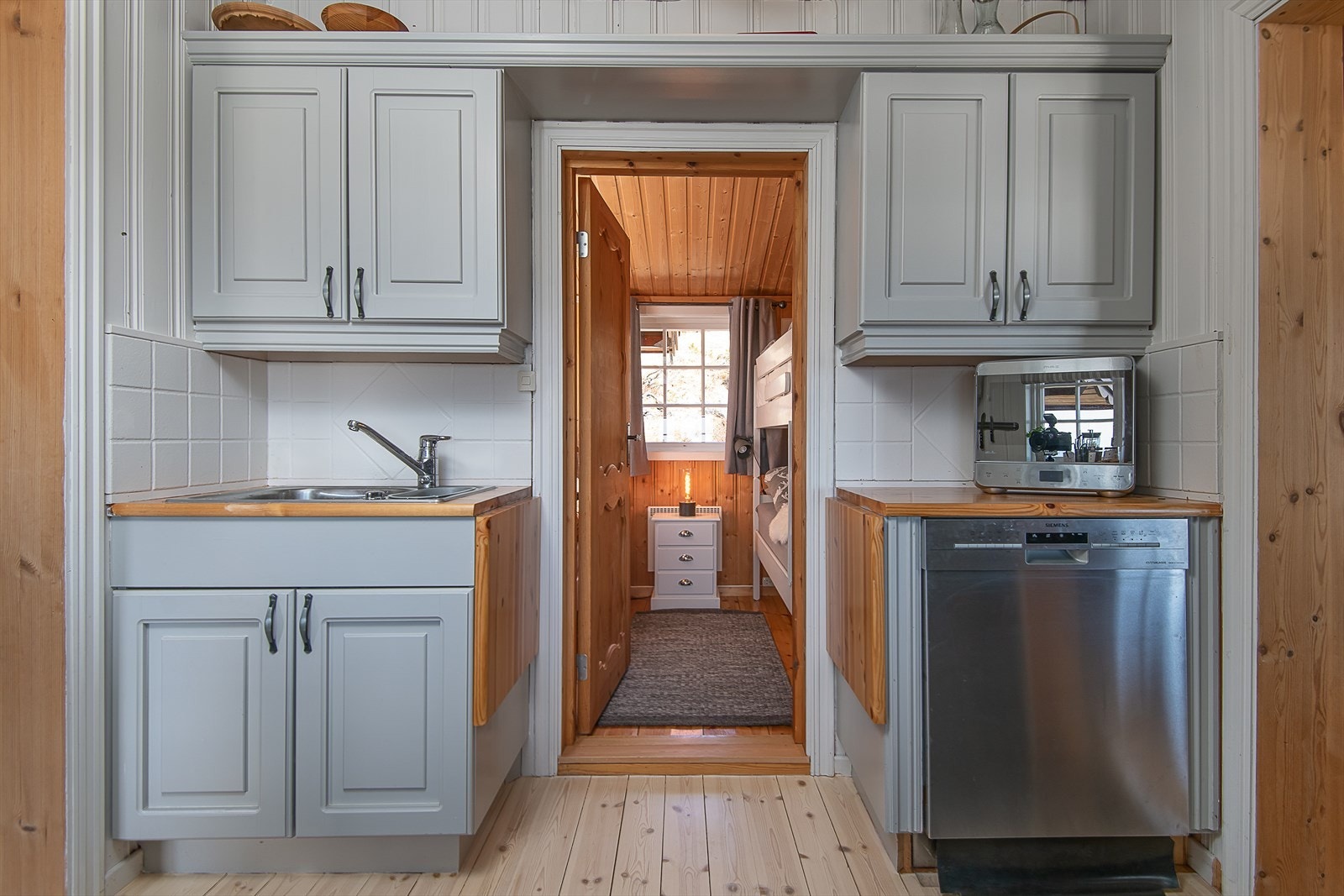 Både over-og underskap er malt i delikat og tidløs gråtone. Det er plass til både oppvaskmaskin og kjøleskap. Integrert komfyr. Galleribilde