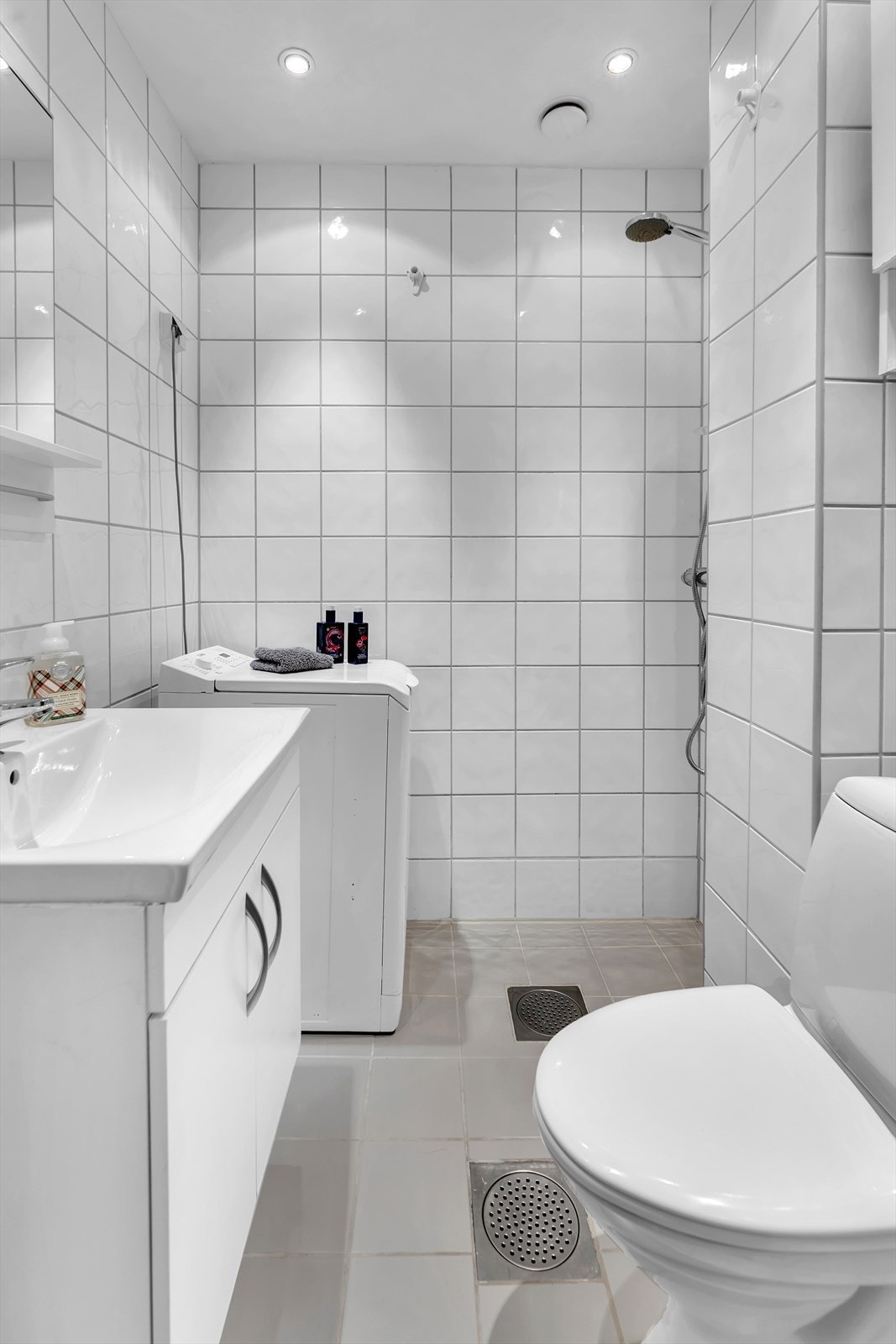 Nøytralt bad med flislagte overflater, gulvvarme og opplegg for vaskemaskin. Galleribilde