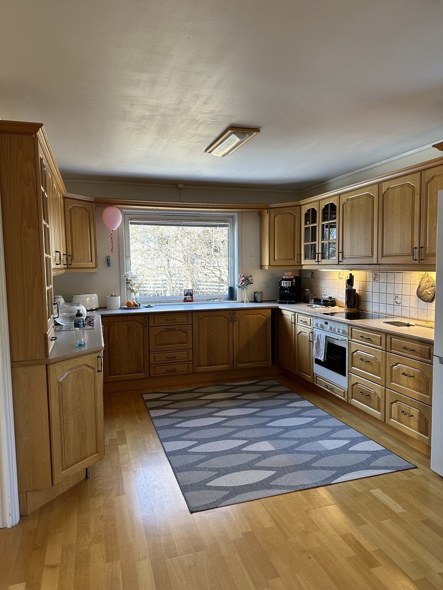 Romslig kjøkken med mye oppbevaringsplass og hvitevarer. Galleribilde