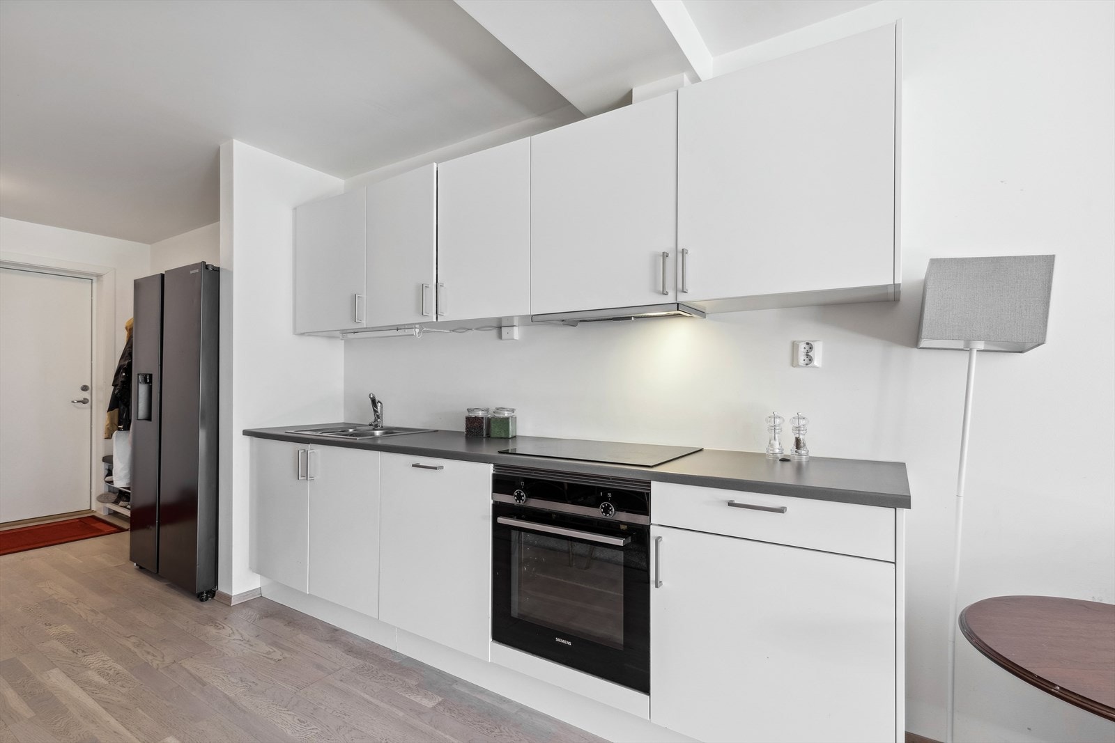 Kjøkkenet har åpen løsning mot stuen. Innredningen har hvite slette fronter og laminert benkeplate. Galleribilde