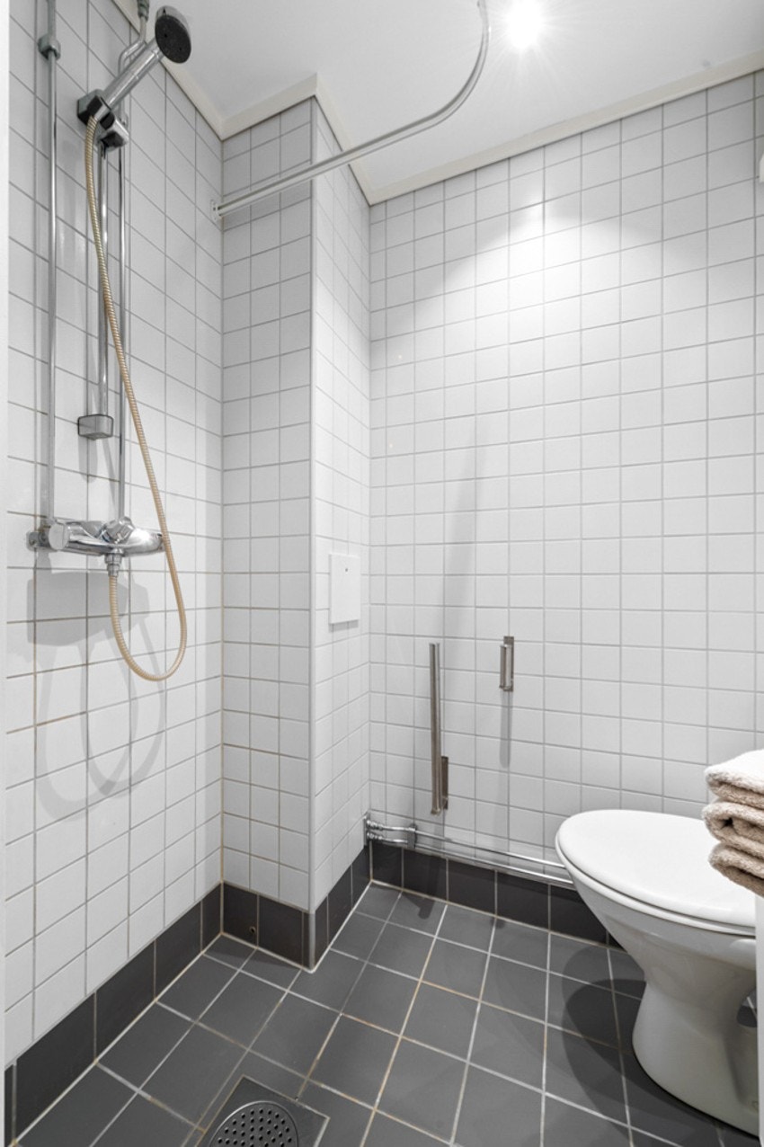 Badet er innredet med dusjhjørne, toalett, speilskap, servant med skap. Det er varmekaber i gulv og spotlights i tak. Galleribilde