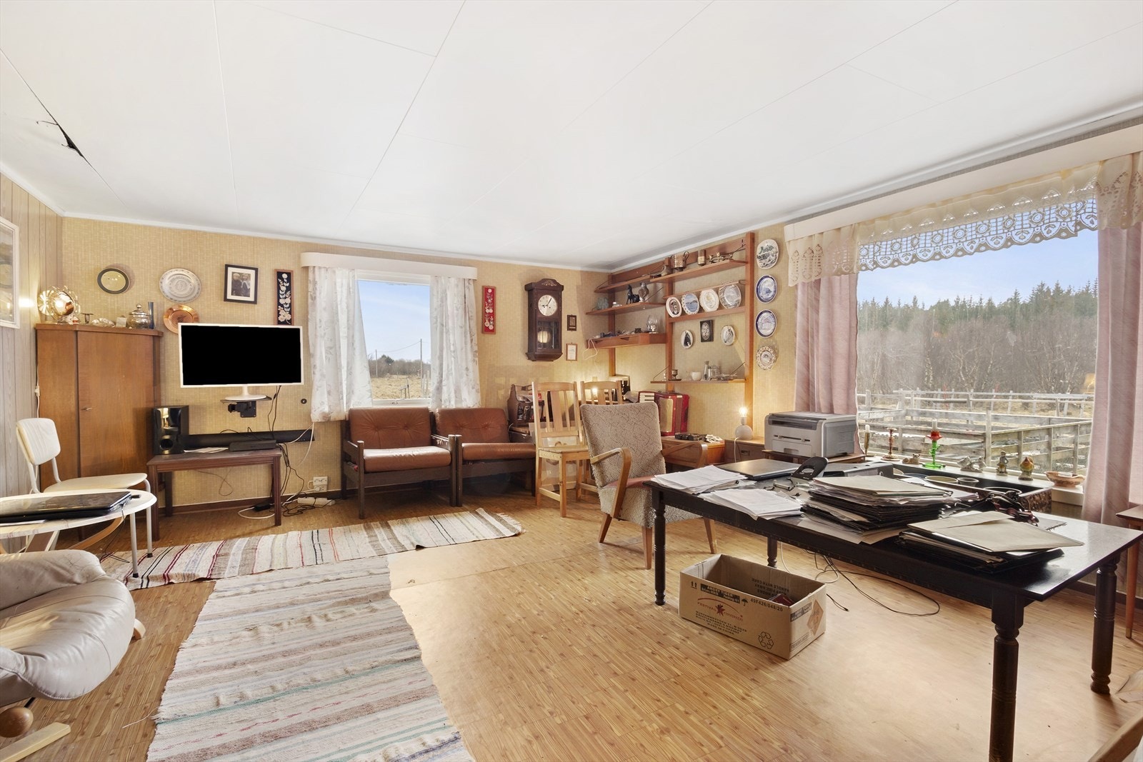 Stuen har et stort vindu vendt mot veien som går forbi eiendommen, rommet er lyst og trivelig Galleribilde