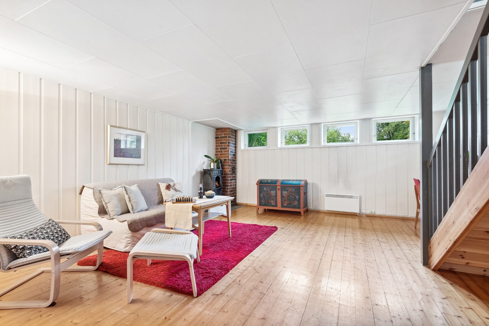 Stuen er romslig med god plass til det møblementet man skulle ønske. Trappen ned fra 1. etasje kommer inn i kjellerstuen. Det er montert vedovn i stuen, denne gir godt med varme i kjellerstuen sammen med panelovnen. Galleribilde