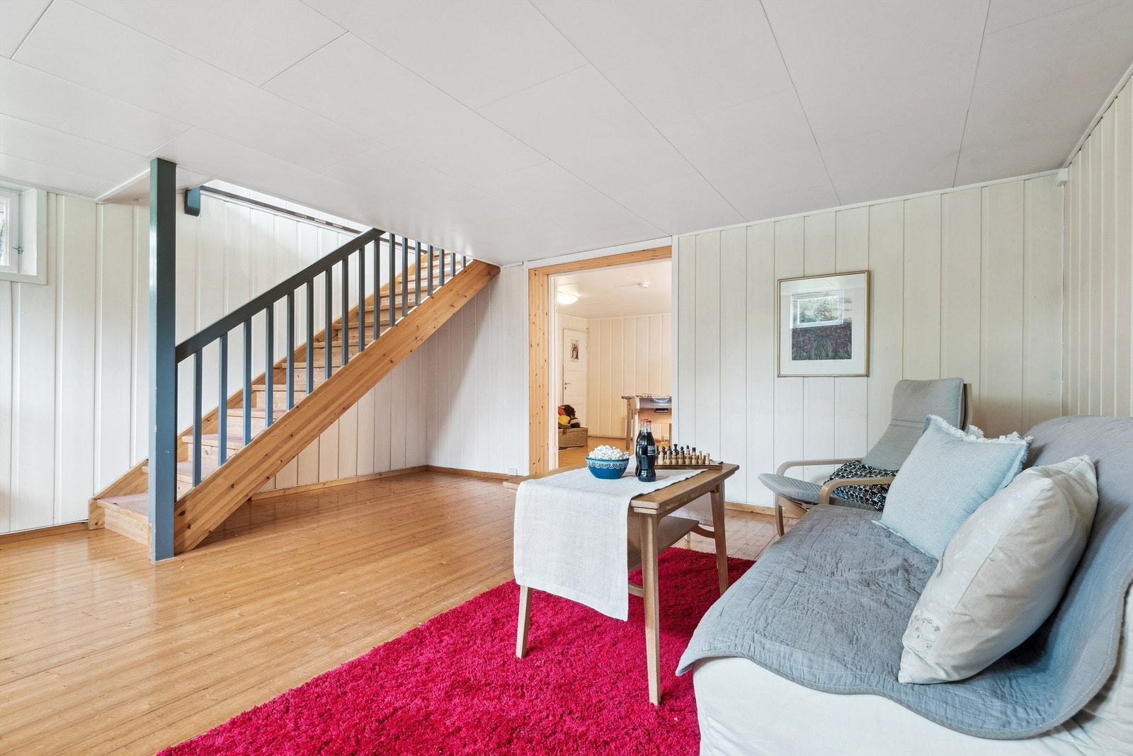 Kjellerstue med malt panel på veggene og heltre gulv. Galleribilde