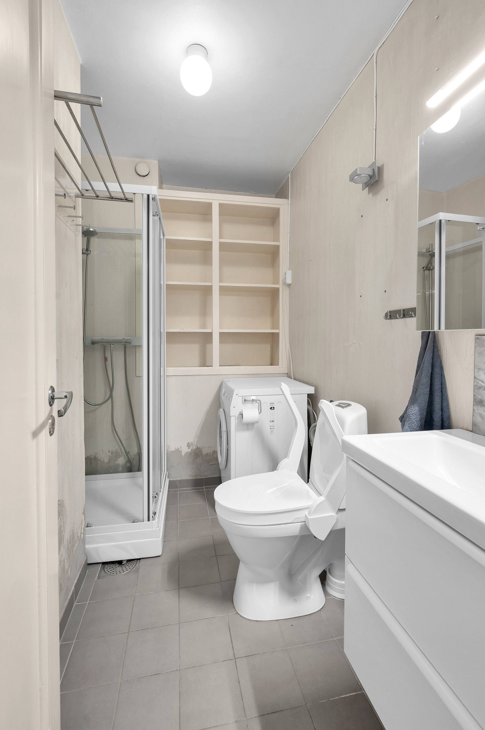 Flislagt baderom med dusjkabinett og toalett med opplegg til vaskemaskin. Galleribilde