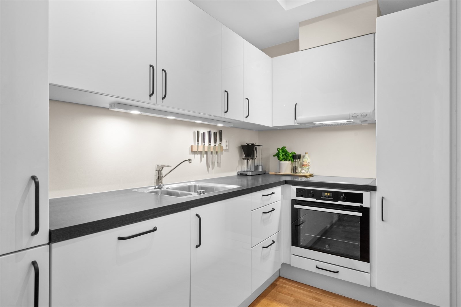 Pent kjøkken med lyse, slette fronter. Integrerte hvitevarer som kjøleskap/fryser, stekeovn, platetopp og oppvaskmaskin. Galleribilde