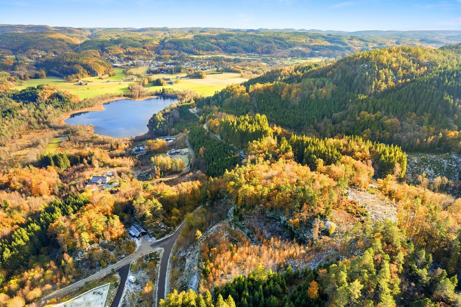 Tomtene ligger på høyden til høyre i bildet. Holmetjørna og Holum sentrum i bakgrunnen. Galleribilde