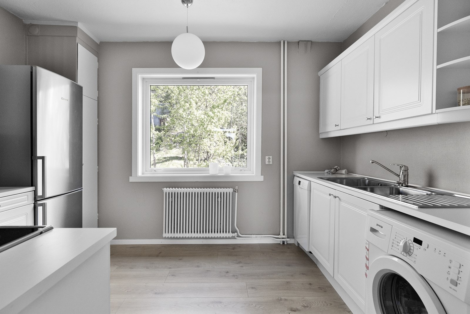 Stort vindu på kjøkken som slipper inn godt med naturlig lys og gir en fin sikt ut til grønne omgivelser Galleribilde