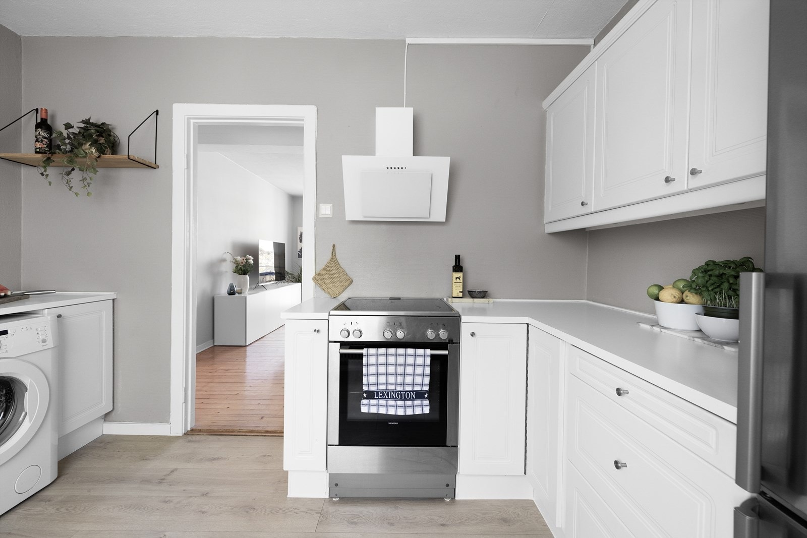 Lys kjøkkeninnredning med over- og underskap, med profilerte fronter og laminat benkeplate Galleribilde