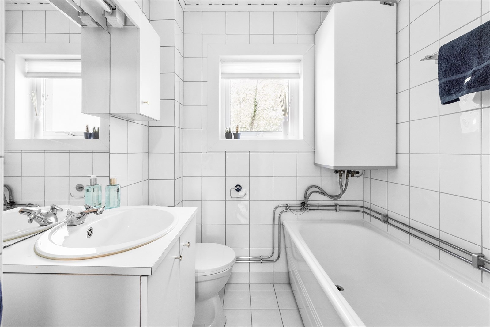 Badet er innredet med servantinnredning med skap, speil med lys over servant og er ustyrt med frittstående toalett og badekar med dusjvegg. Galleribilde