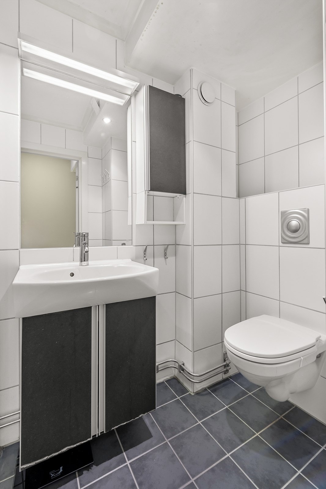 Badets innredning består av dusjhjørne, servant med underskaper, speil, vegghengt toalett og opplegg til vaskemaskin og tørketrommel. Galleribilde