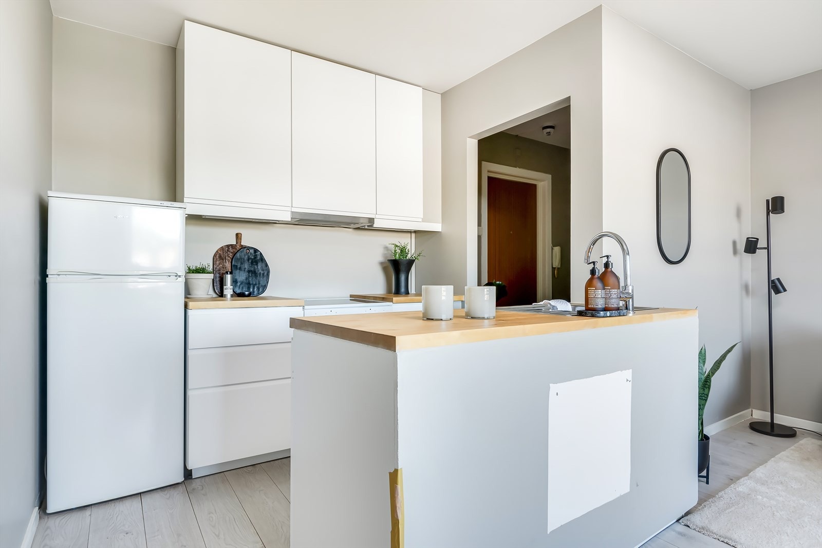 Hvit, stilren kjøkkeninnredning med rikelig skap- og benkeplass Galleribilde