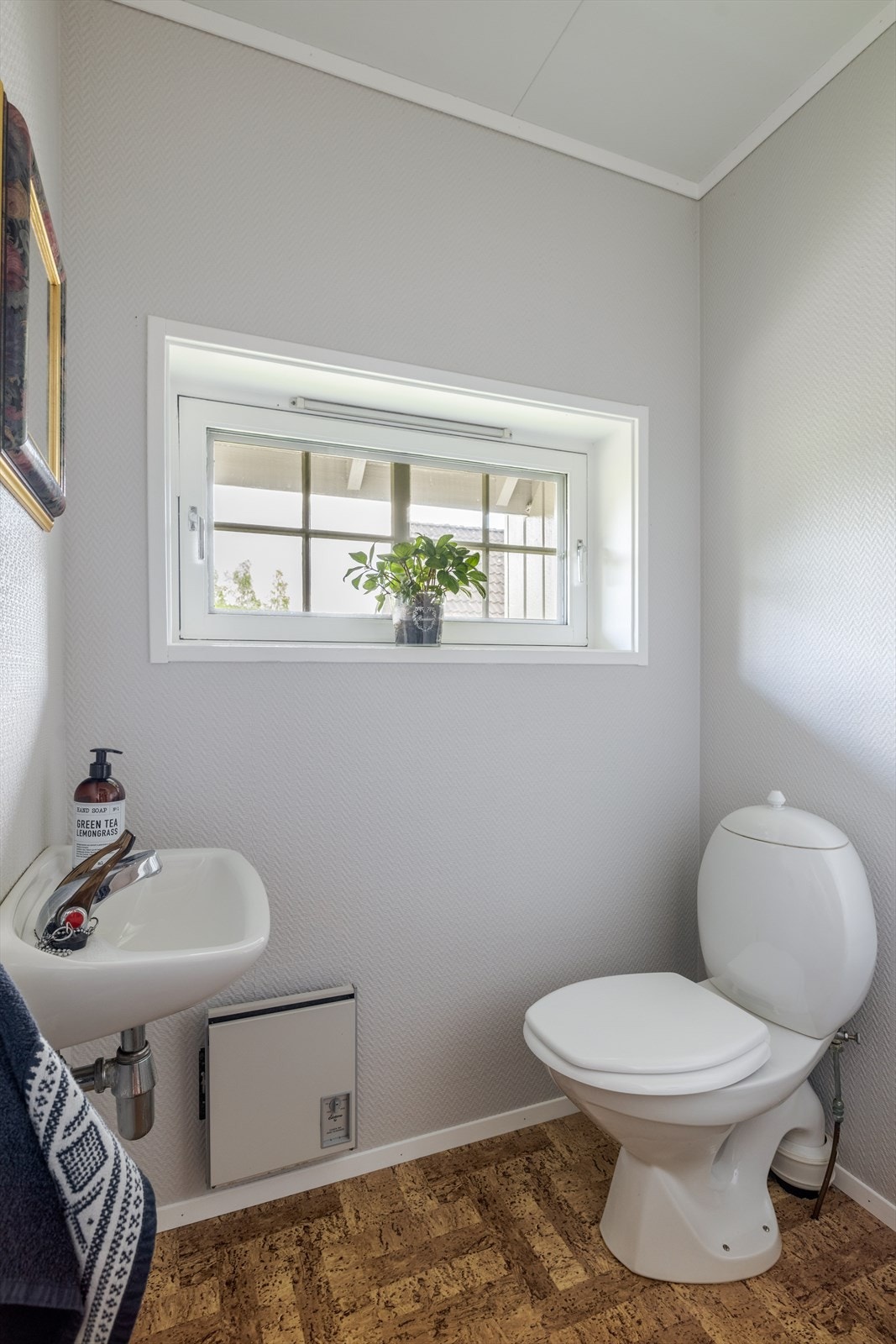 Boligen har eget toalettrom nede ved inngangspartiet. Rommet er innredet med servant og toalett, og overflater er belegg på gulv, tapet på vegger og takessplater i tak. Galleribilde