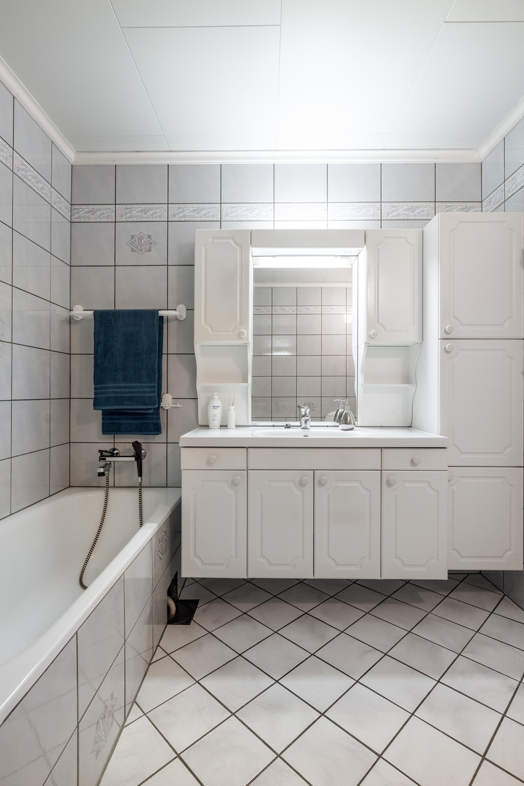 Badet fra 1991 er helfliset og har varmekabler i gulv. Her er det godt med oppbevaringsplass i hvit innredning med heldekkende servant, høyskap og overskap. Galleribilde