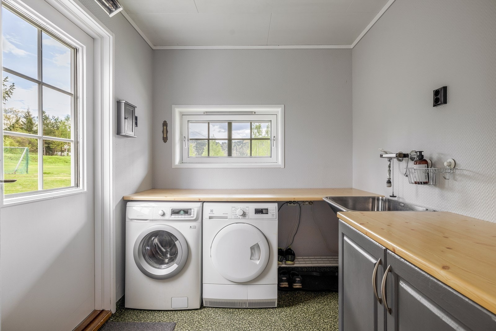 Inntil hallen ligger vaskerommet, hvor det er egen dør med utgang mot inngangspartiet. Vaskerommet er meget praktisk innredet, med god benkeplass og underskap for oppbevaring. Både vaskemaskin og tørketrommel er praktisk plassert under benk. Galleribilde