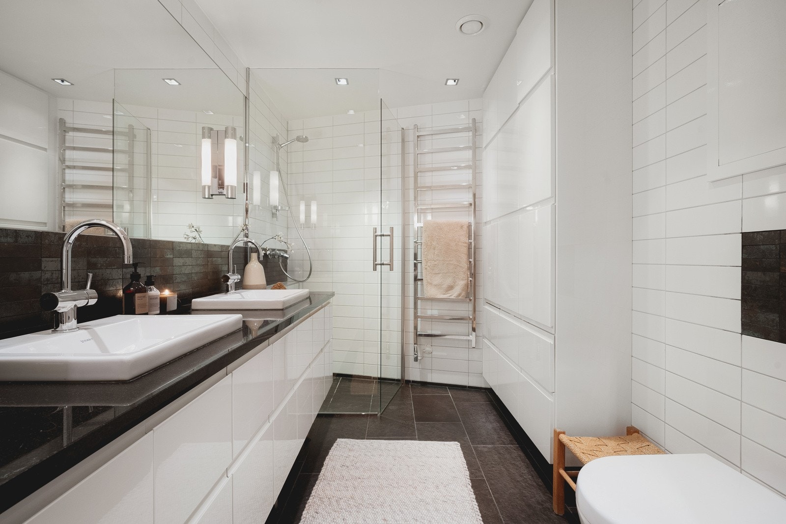 Badene har den samme tidløse stilen, med bl.a. fliser som går igjen fra kjøkkenet, store dusjhjørner og praktisk vegghengt toalett. Galleribilde