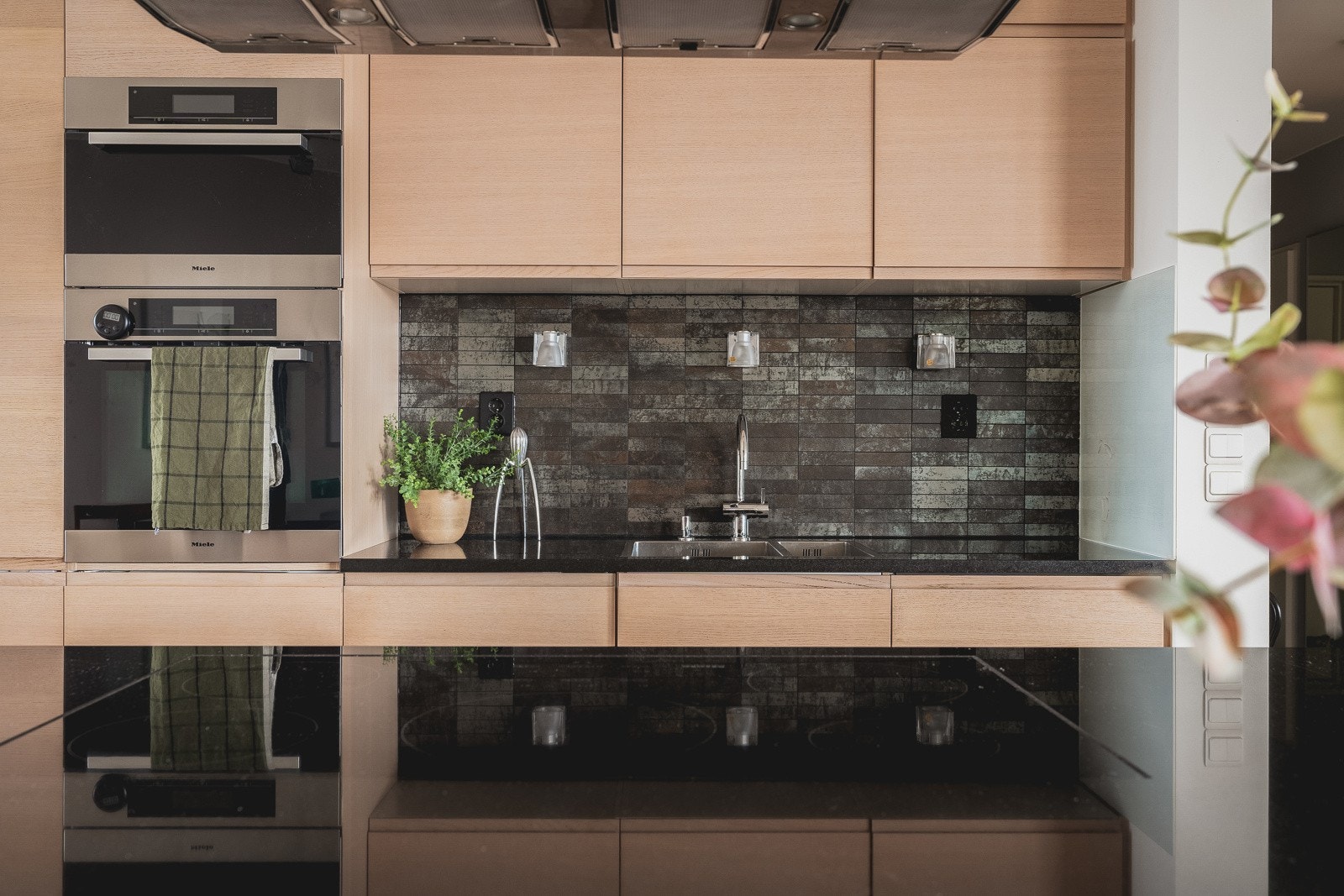 Moderne design og nøye utvalgte detaljer som fliser mellom over- og underskap, samt benkeplate i stein, gir kjøkkenet et eksklusivt preg. Galleribilde