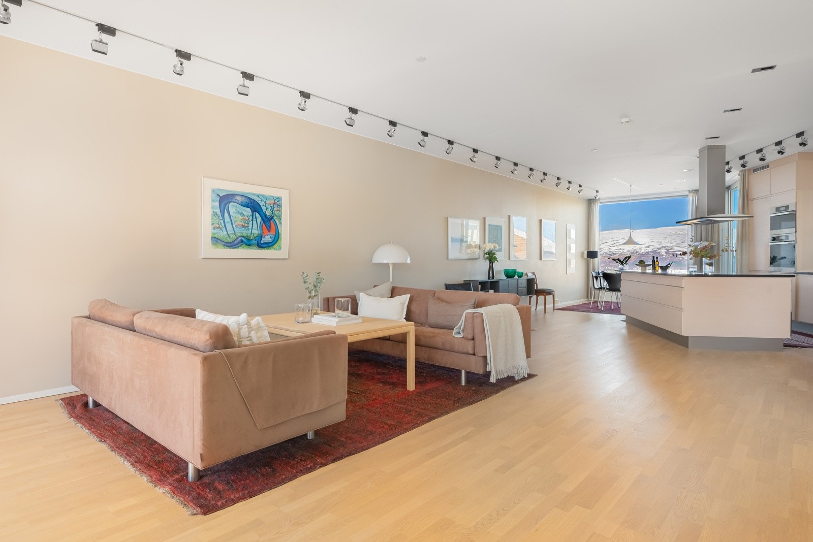 Den åpne planløsningen mellom stue og kjøkken gjør rommet ekstra lyst og luftig, ideelt for både hverdagsliv og sammenkomster. Galleribilde