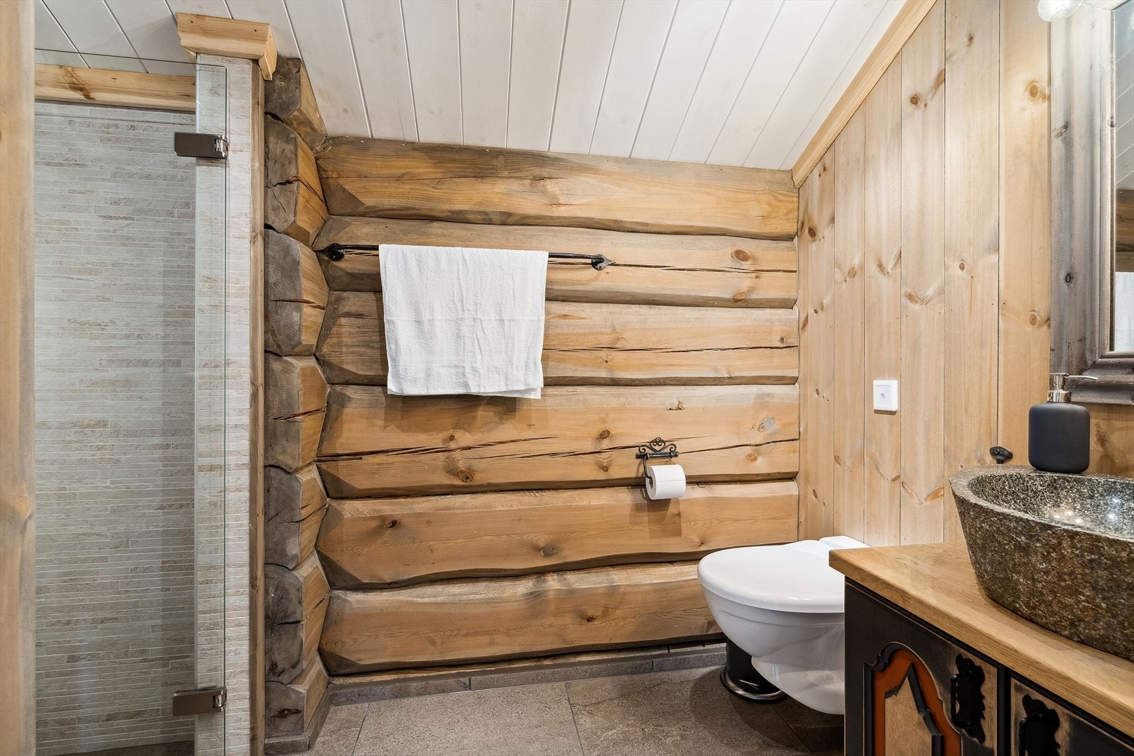 Bad i loftsetasjen, med veggmontert toalett, dusjnisje og innredning med servant av stein. Galleribilde