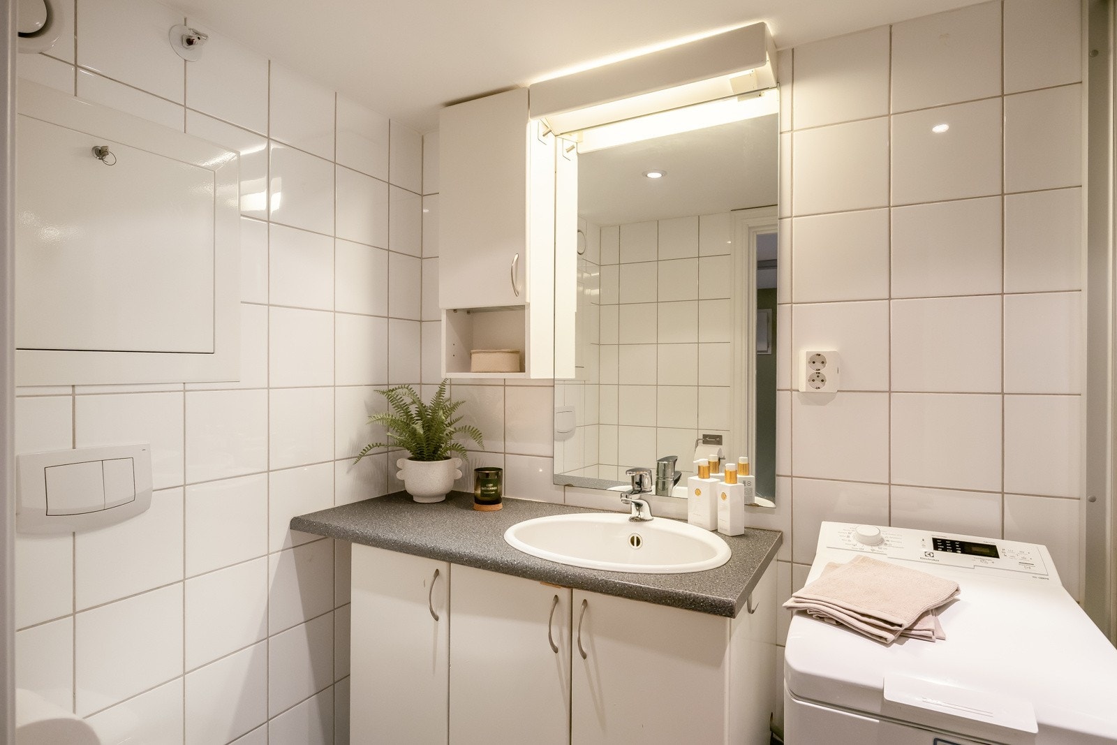 Badet er utstyrt med servant med underskap, opplegg for vaskemaskin, dusjnisje med skyvedør, og vegghengt toalett. Galleribilde