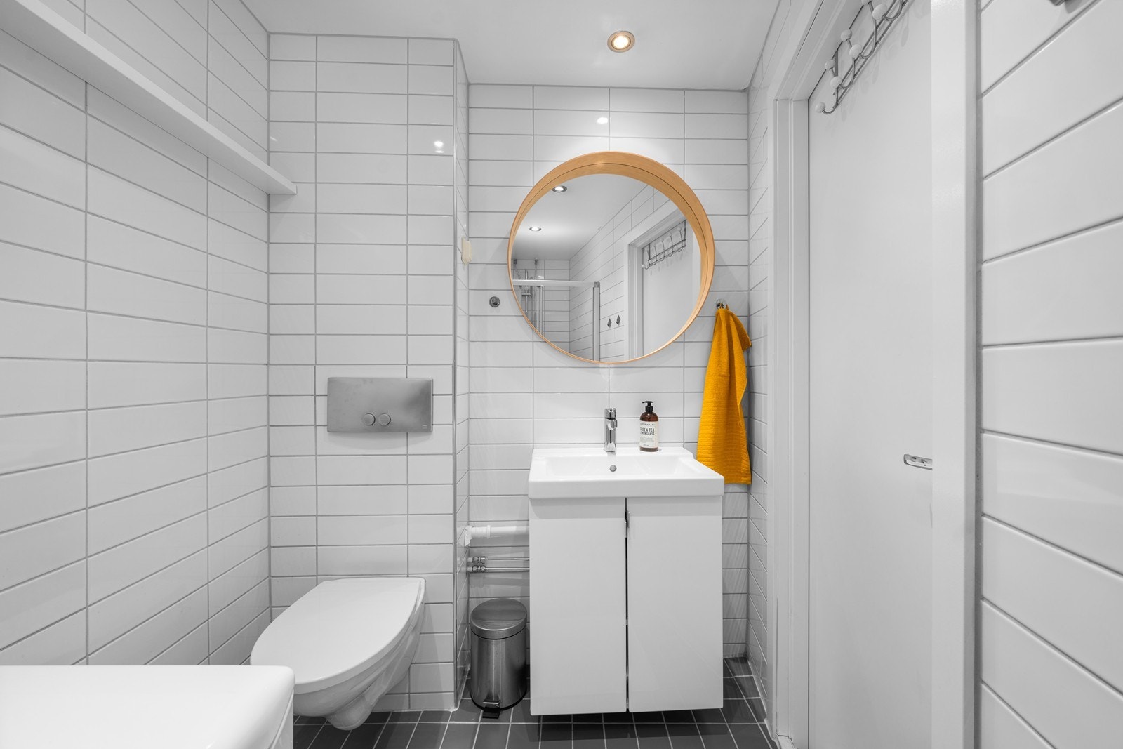 Baderomsinnredningen består av et stort dusjhjørne med skyvedør, vegghengt wc, servantskap med lakkerte hvite fronter og helstøpt vask. Galleribilde