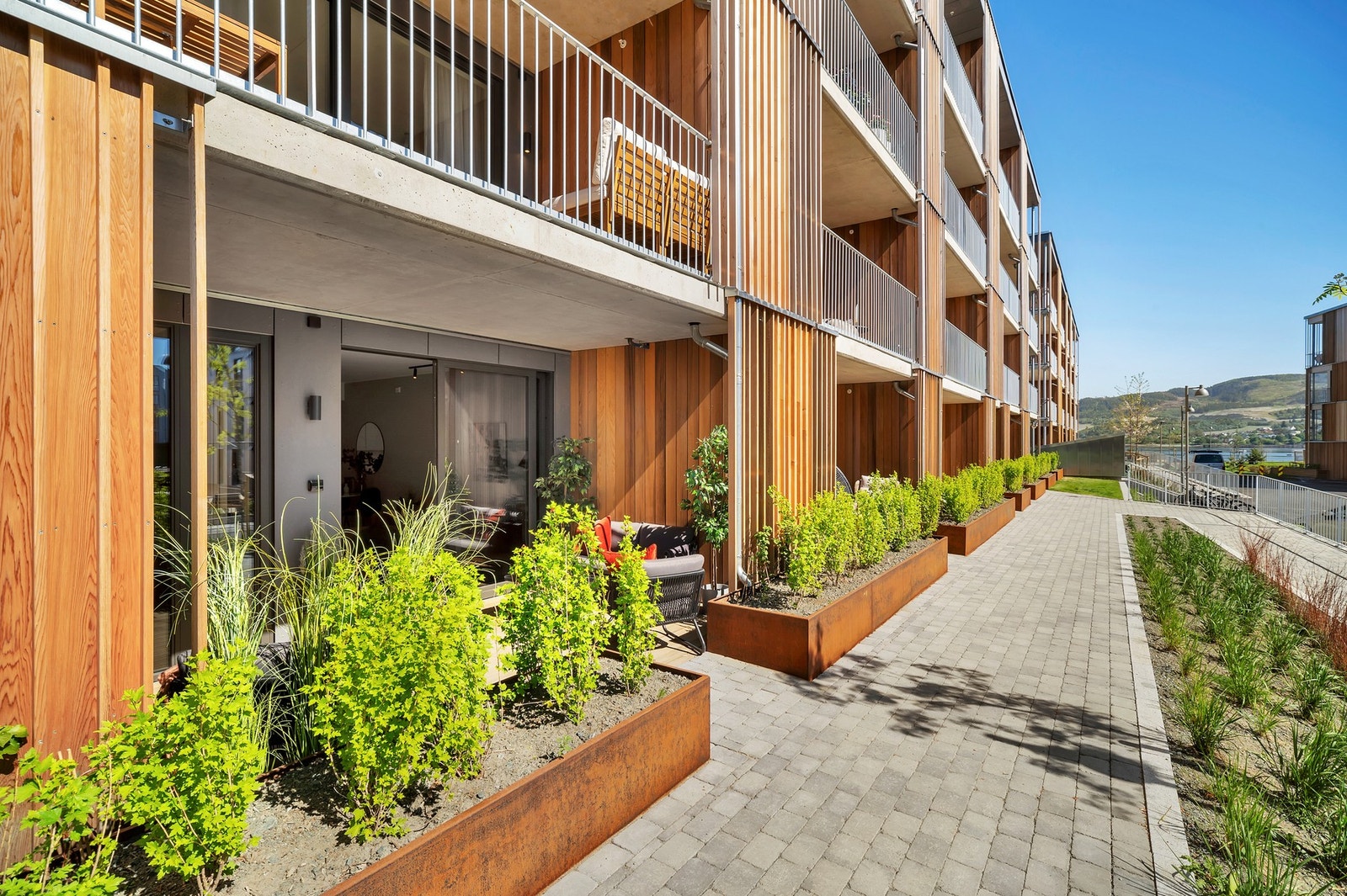 Store blomsterkasser i cortenstål bidrar til å skjerme terrassen. Galleribilde