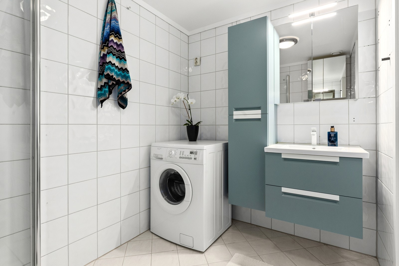 Badet er pent flislagt og utstyrt med dusjhjørne, servantskap, sideskap, speilskap samt gulvstående wc og elektriske varmekabler for ekstra komfort. Galleribilde