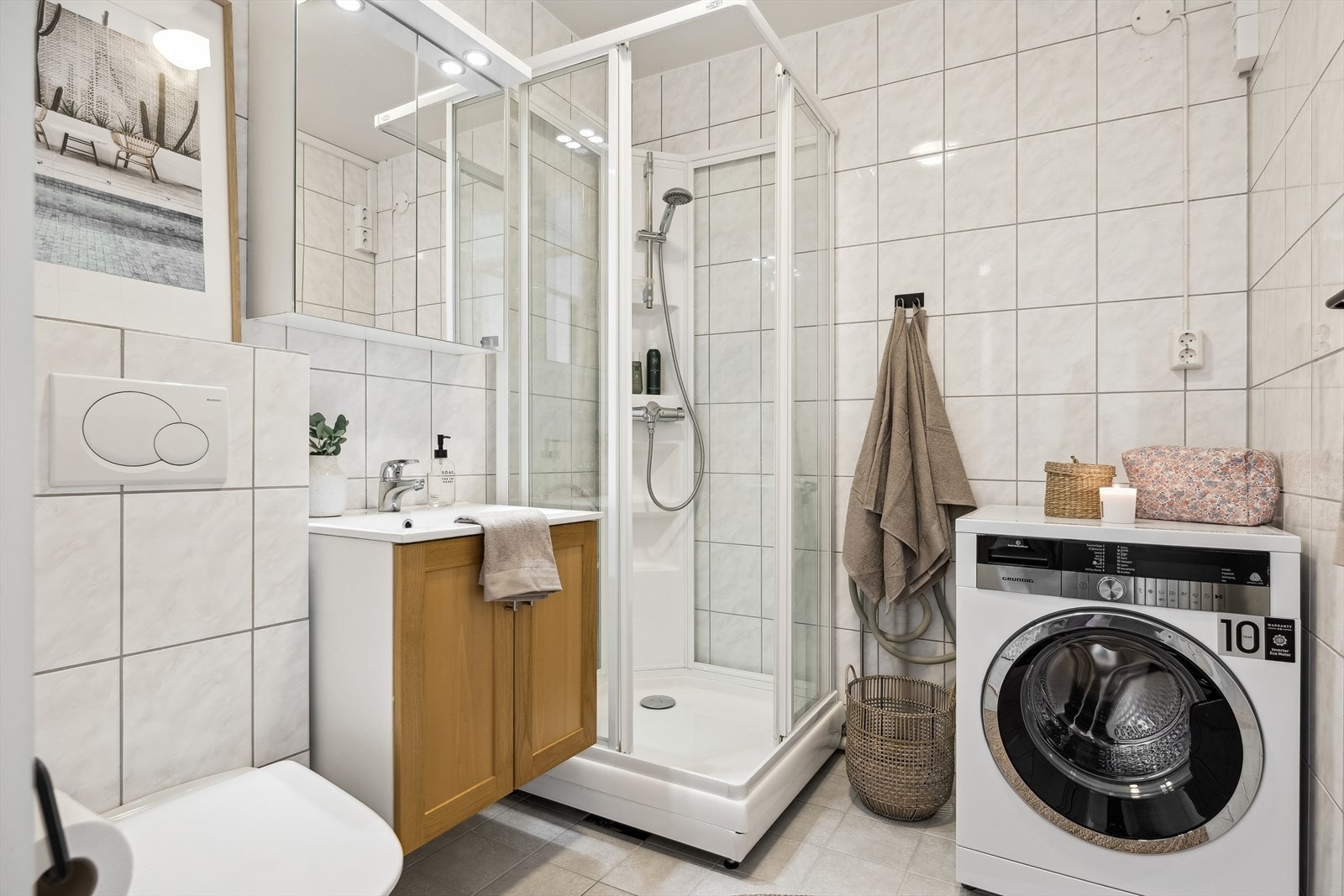 Badet er helfliset, innredet med gulvvarme, dusjkabinett og opplegg for vaskemaskin. Galleribilde