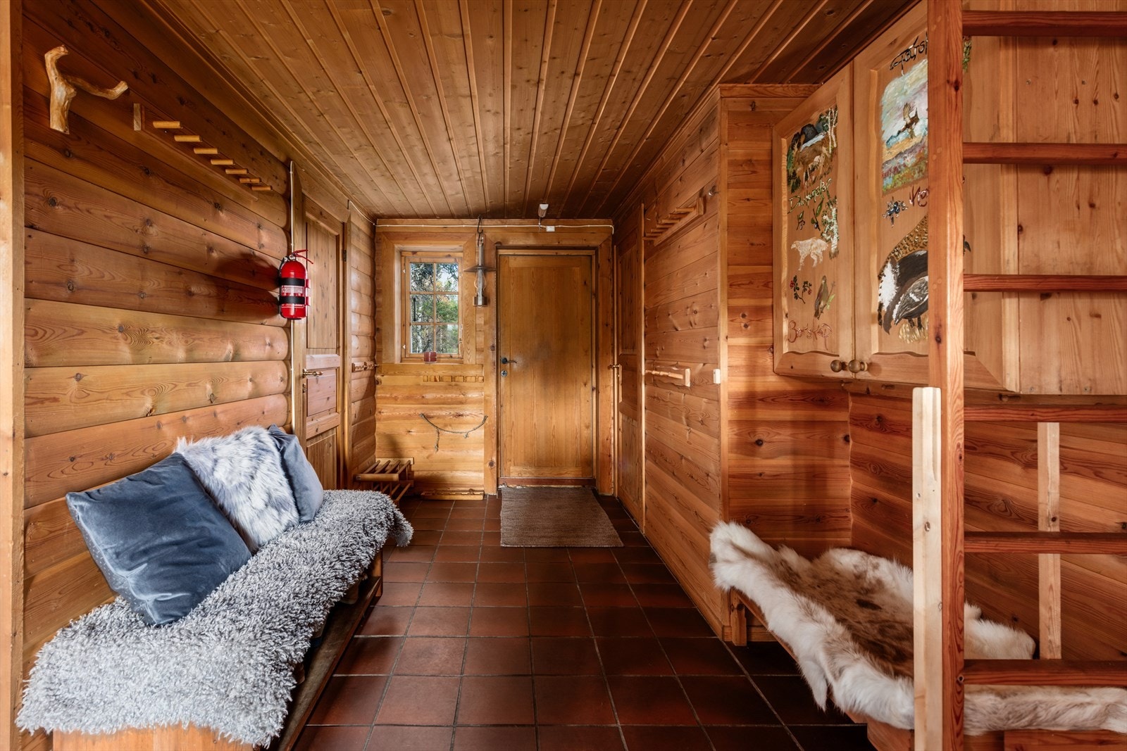 Gang med adkomst til hemsareal og utgang til baksiden av hytta. Ved utgangen har man to boder på hver side av døra. Galleribilde