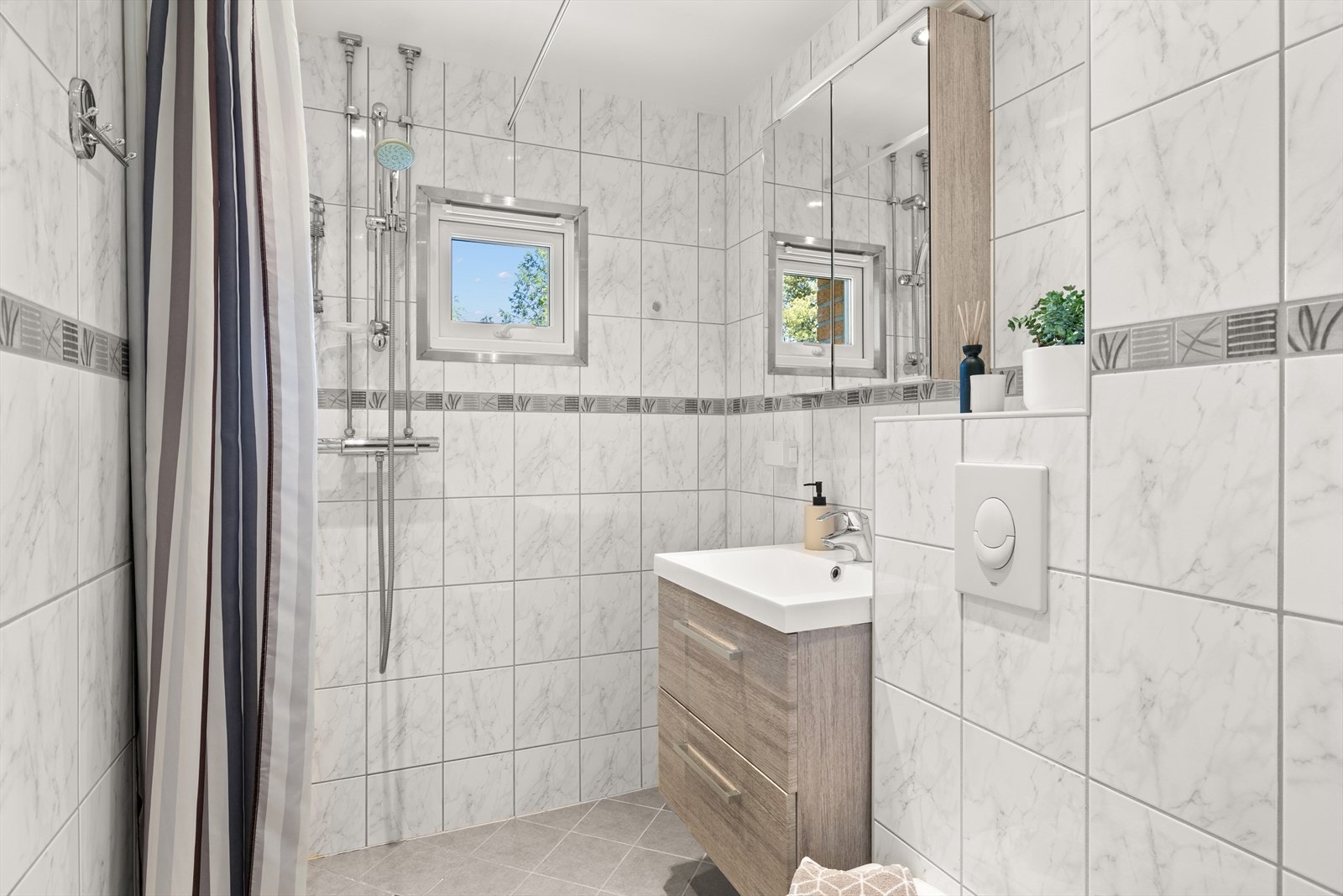 Badet er av god størrelse med varme i gulv, innfelte downlights og praktisk innredning Galleribilde