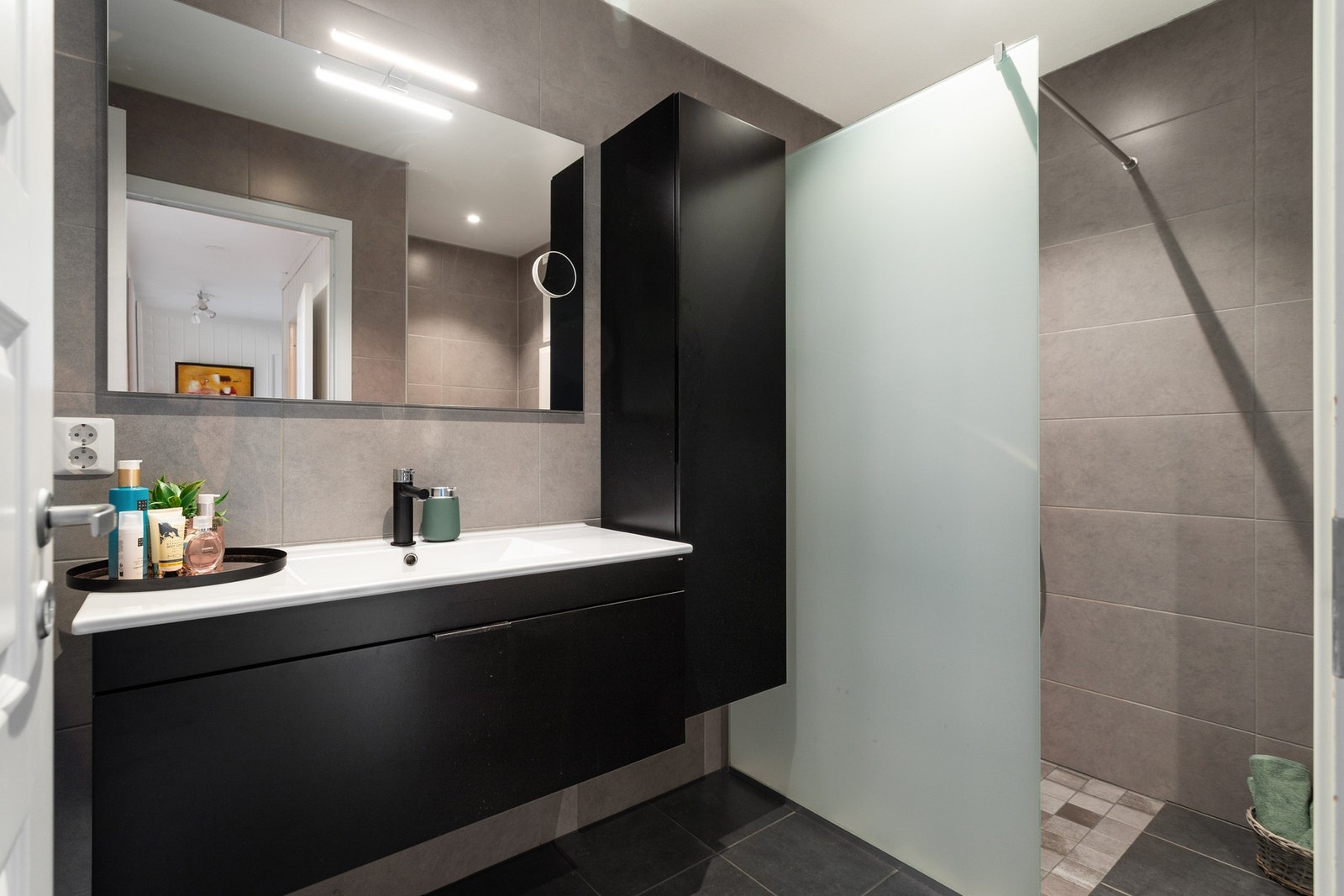 Flis på gulv og vegger, med dusjhjørne og vegghengt toalett. Galleribilde