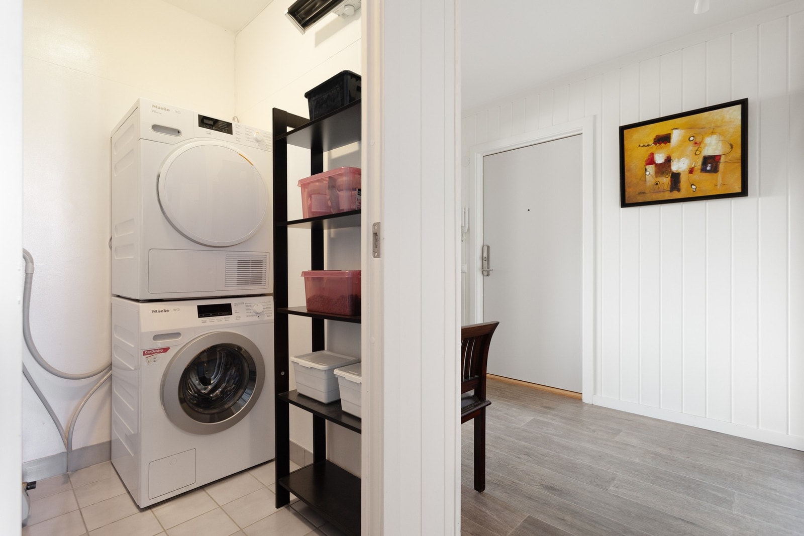 Praktisk eget vaskerom med flis på gulv og opplegg for vaskemaskin. Galleribilde