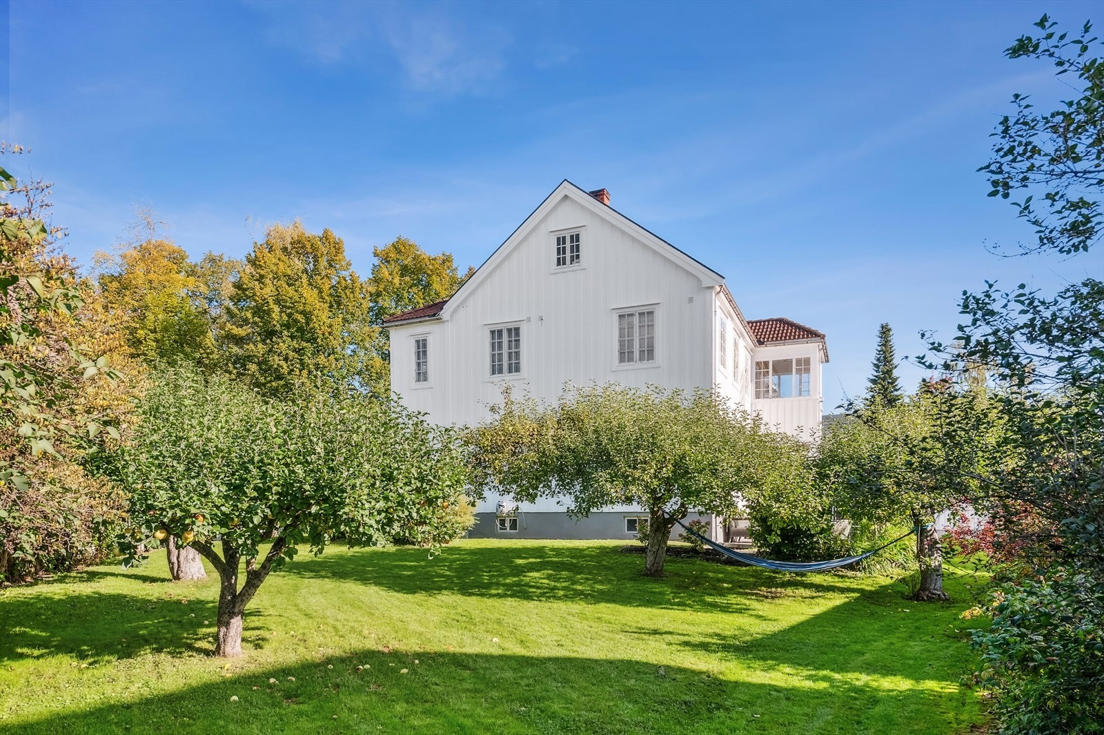 En romslig og pen opparbeidet eiendom med platting, plen og diverse beplantninger. Galleribilde