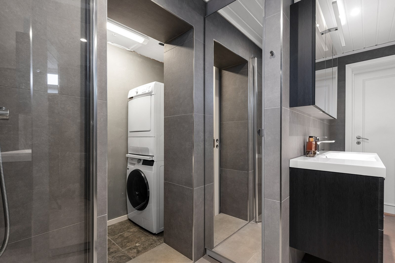 Et smart vaskerom i tilknytning til badet som kan lukkes med skyvedør Galleribilde