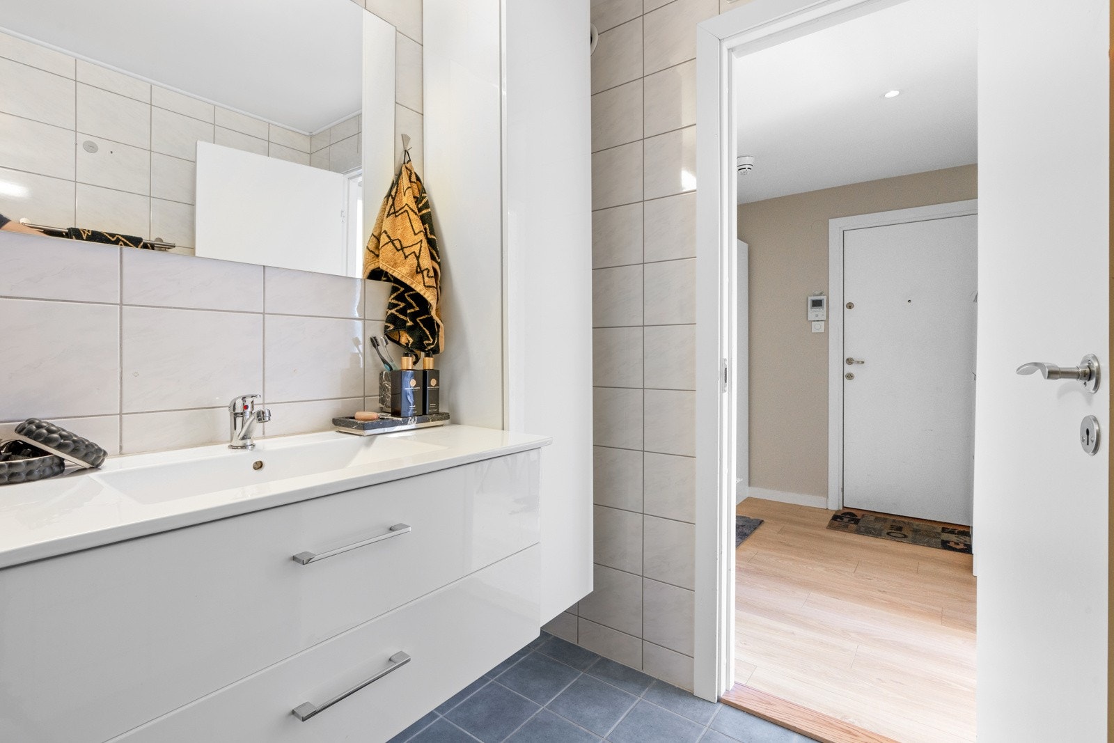 Stor, hvit servantinnredning med hvit heldekkende servant og speil på vegg. Galleribilde