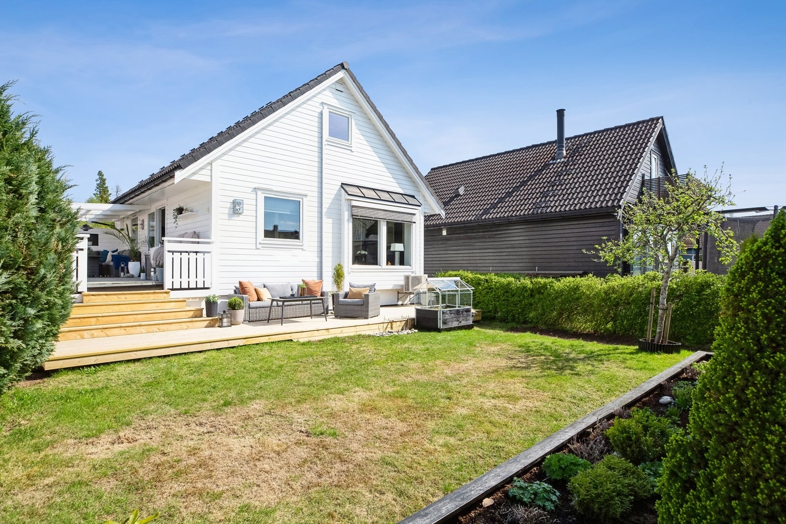 Hagen har plen, hekk, gjerde, trær og diverse beplantning. Galleribilde