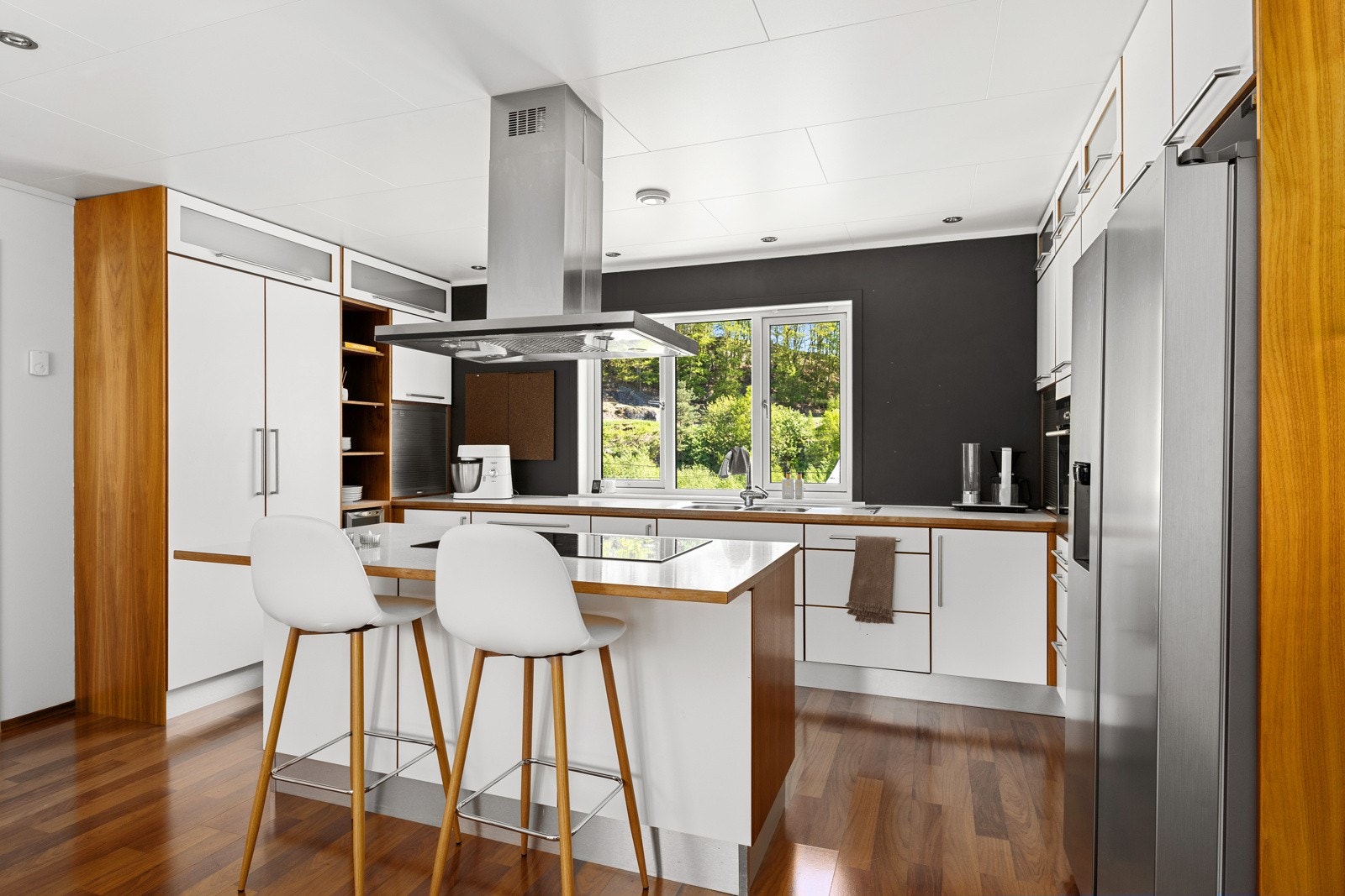 Kjøkkenet er lekkert utført med hvite overflater og tredetaljer. Galleribilde