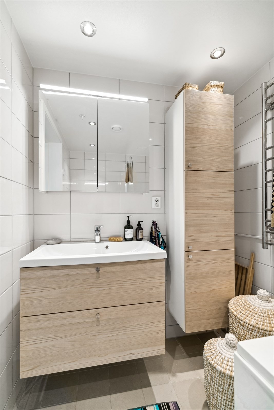 Boligen har to romslige baderom. Badet i 1.etasje er flislagt og innredet med servantinnredning med skuffer, overskap med speil og høyskap. Varmekabler i gulv. Galleribilde