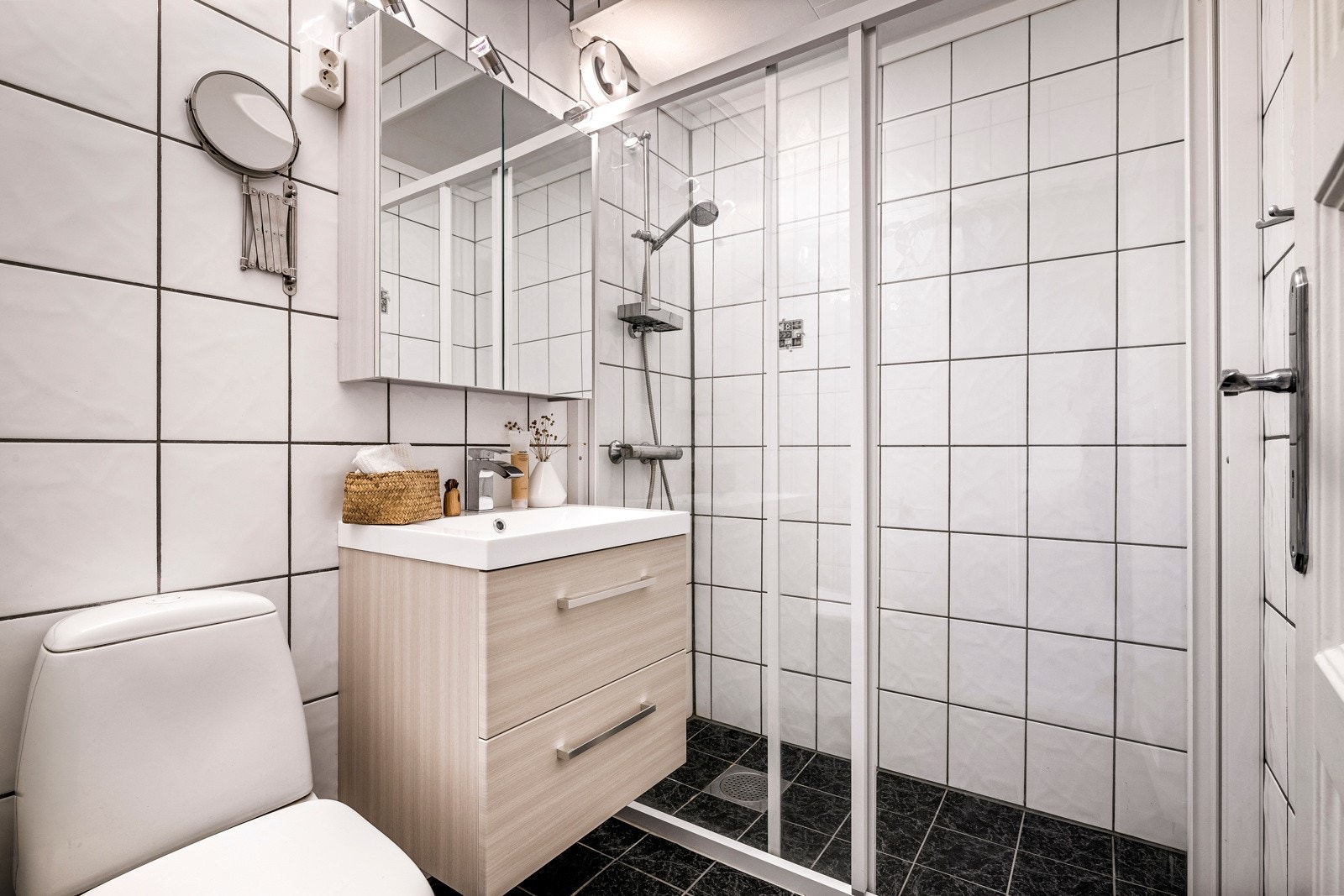 Baderomsinnredningen består av benkeskap med servant, dusjdører med gulvskinne og gulvmontert toalett. Galleribilde