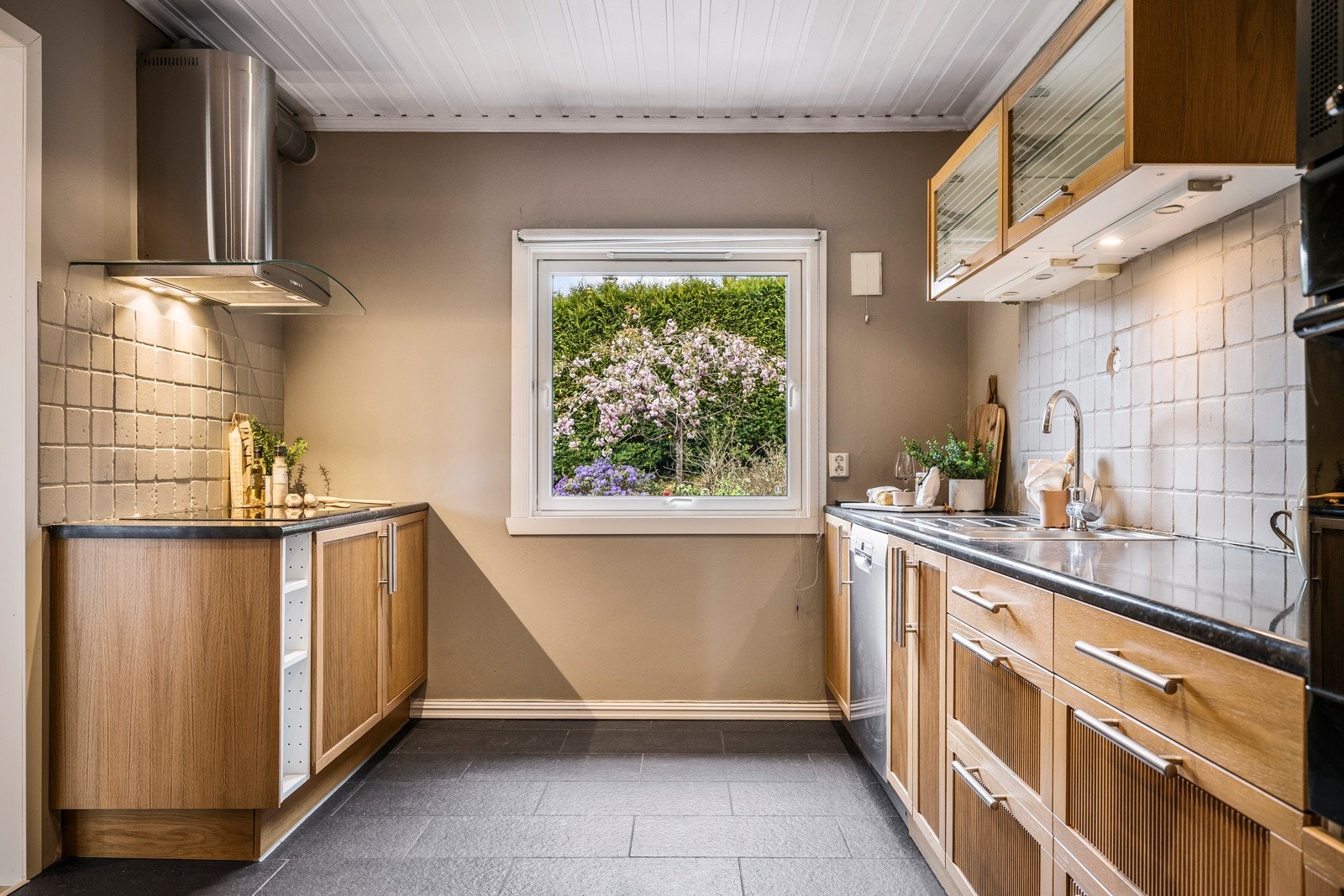 Kjøkkeninnredning med profilerte fronter og benkeplate i laminat. Integrert i innredningen er det stekeovn og induksjonsplatetopp. Galleribilde