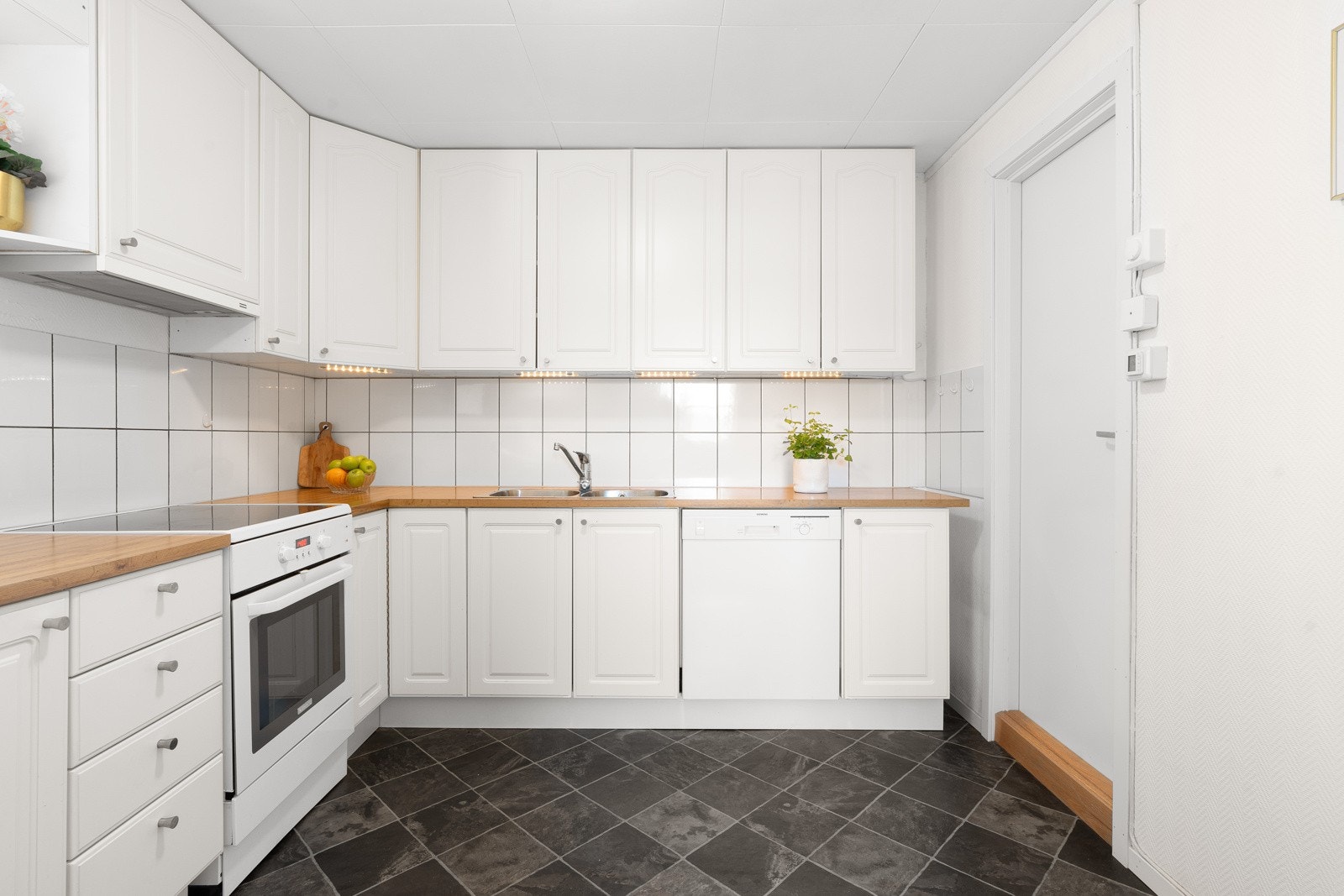 Kjøkkeninnredning med lyse, profilerte fronter, takhøye overskap og laminat benkeplate med dobbel nedfelt oppvaskkum Galleribilde