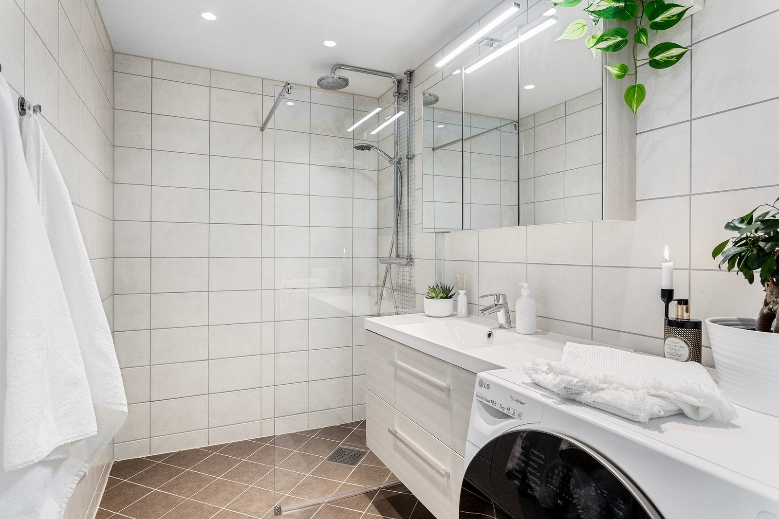 Lyst, flislagt baderom med gulvvarme og downlightsbelysning i taket. Badet ble pusset opp i regi av borettslaget i 2017 og fremstår moderne. Her er det opplegg for vaskemaskin. Galleribilde