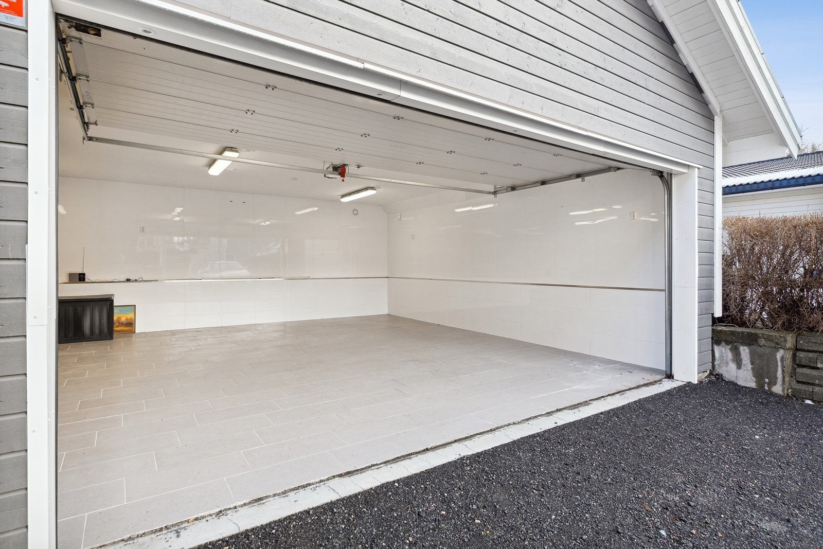 Garasjen har leddport, flislagt dekke og varmepumpe. Galleribilde